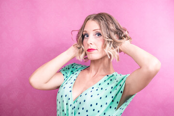 Vintage portrait of a woman, posing, dressed in green, in a pink background, with a vinyl record in her hand.