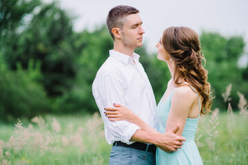 Fototapeta premium happy guy in a white shirt and a girl in a turquoise dress are walking in the forest park