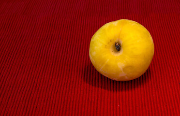 Large yellow plum on red cloth napkin on the table closeup, closeup , selective focus