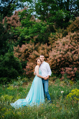 Fototapeta premium happy guy in a white shirt and a girl in a turquoise dress are walking in the forest park
