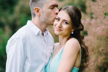 Obraz premium happy guy in a white shirt and a girl in a turquoise dress are walking in the forest park
