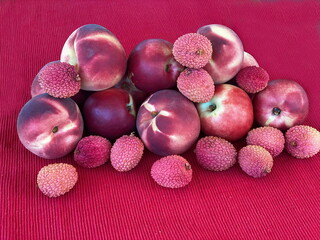 Mix fruit: fresh red peaches, nectarine and lychee on red cloth napkin