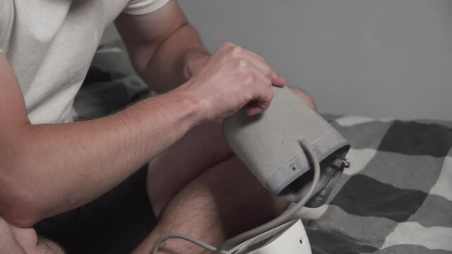 Young man measuring blood pressure at home. Hypertensive patient performing an automatic blood pressure test. Doing my regular checkup. High blood pressure hypertension disease. Automatic tonometer