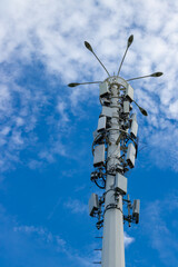 Obraz premium A telecommunication signal tower with blue sky and white clouds as the background.