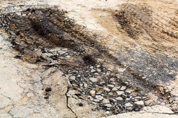 A road damaged by rain and snow, that is in need of maintenance. Broken asphalt pavement resulting in a pothole, dangerous to vehicles.