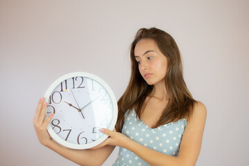 Pretty girl in dress looking at a big clock