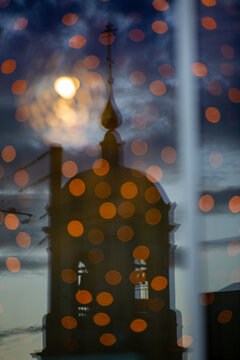 Unfocused reflect of church and thunders sky in glass . A lot of bokeh from street lights