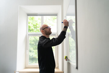 Portrait of young man in eyewear writing on white board during a presentation in conference room