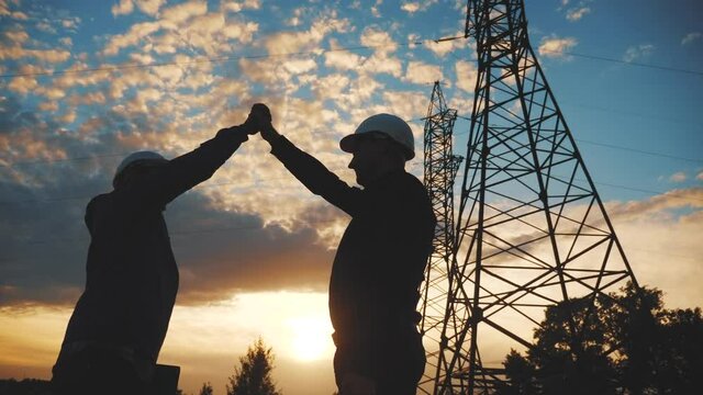 teamwork. two electricians engineer shake hands. business partnership energy technology industry a concept. silhouette two workers handshake. lifestyle teamwork in energy
