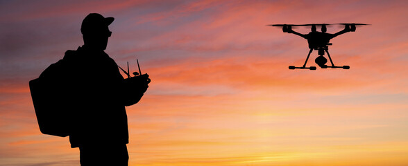 Silhouette of a man controls a drone on a sunset background
