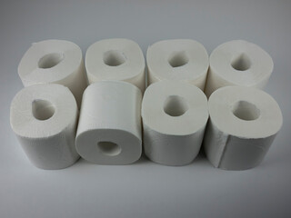 rolls of white toilet paper on a white table.