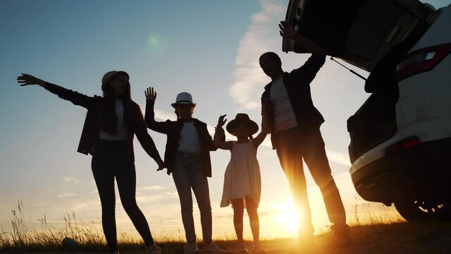 happy family wave goodbye campsite on a car outdoors silhouette at sunset. parents and kid children waving hands at the sunset nature. day off holiday friendly family dream teamwork concept. happy