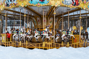 Children's carousel with horses in the winter snow-covered park