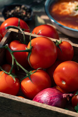 Close-up of fresh, ripe tomatoes and purple onion. Tomato soup behind it.