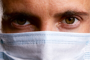 gros plan yeux jeune homme beau médecin portant un masque de protection antivirus médical en papier pour protection contre le covid-19  - obrazy, fototapety, plakaty