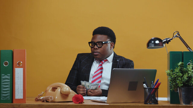 Successful black afro businessman financial manager takes bunch of money counting salary payday advance sitting at desk in his office corporation. Concept of career.