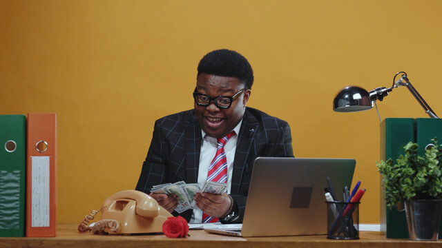 Satisfied african employee receives bunch of money on payday. Handsome happy black businessman counts money banknotes working at modern office corporation.