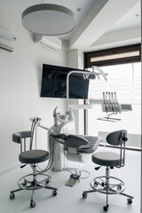 Interior of dental practice room with chair, lamp, display and stomatological tools