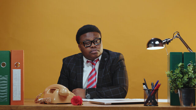 Positive afro-american trade manager in suit glasses sits at working table smiles happy successful staying in modern office corporation. Young business people.