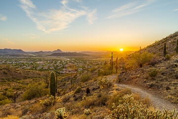 A desert trail on a mountain leading to a sunset over a valley in Phoenix, Arizona.