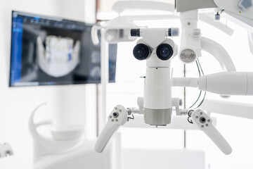 Interior of dental practice room with close up on microscope and dental scan on the display....