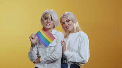 Tender Lgbt female couple family girls tightly hug each other and hold rainbow flag symbolizing love equality and freedom. Lgbt lesbian community.