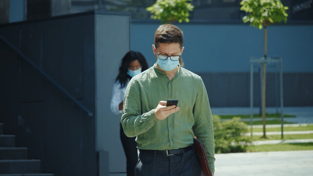 Young businessman with laptop wearing respiratory mask on face using mobile phone on office break Business people lifestyle. Corporate. Communication.