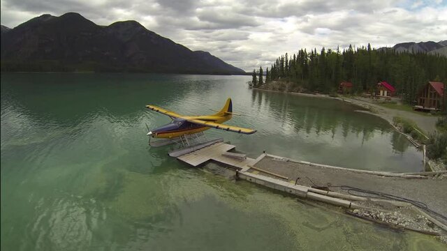 AERIAL FLY OVER OF FLOAT PLANE AT DOCK ON BEAUTIFUL LAKE IN CANADA