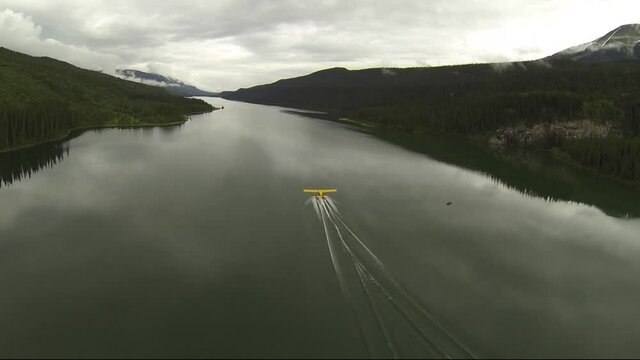 AERIAL CHASE SHOT OF FLOAT PLANE TAKE OFF IN LAKE BC CANADA