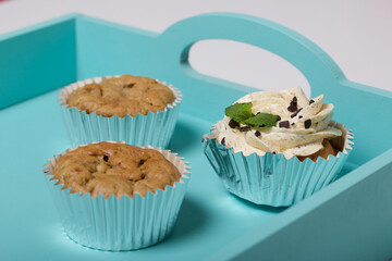 Banana cupcake. With butter cream and banana jam. Decorated with mint leaves and chocolate sprinkles. Next to them are cupcakes without cream