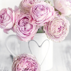 Beautiful fresh roses in a porcelain cup decorated with a heart. Pink roses on a white background.

