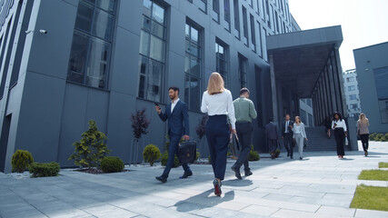 Multi-ethnic young business persons corporate workers walking outside company in modern district downtown. Office people diversity. Urban lifestyle.
