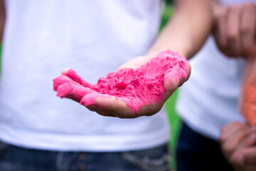 colored pink powder for traditional holi festival in hand close-up. man in a white t-shirt on the background.