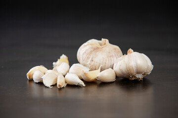still life arrangement of Three whole garlic bulbs grouped on black stone plate