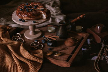 Still life of apple pie, berries, coffee and lemons on wooden tray