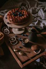 Still life of apple pie, berries, coffee and lemons on wooden tray