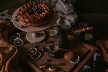 Still life of apple pie, berries, coffee and lemons on wooden tray