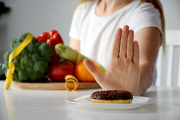 Hands of woman refusing from dessert in favor of vegetables. Balanced diet, healthy nutrition, clean eating, weight loss or detox concept.