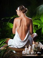 View of nice young woman meditating in spa tropic environment