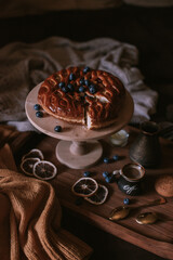 Still life of apple pie, berries, coffee and lemons on wooden tray