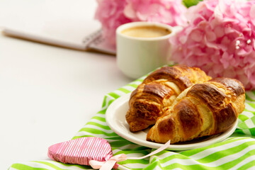 Breakfast with croissants, pink rose flower, petals, vintage plates and black coffee composition. Flat lay, top view