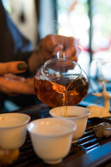 Traditional Chinese Tea Ceremony. Black or Red Tea pouring into White pial cup on dark Table background