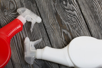 Fototapeta premium Plastic bottles of white and red color with a spray gun. Cleaning spray. Against a background of painted boards.