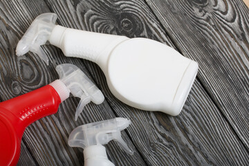 Plastic bottles of white and red color with a spray gun. Cleaning spray. Against a background of painted boards.