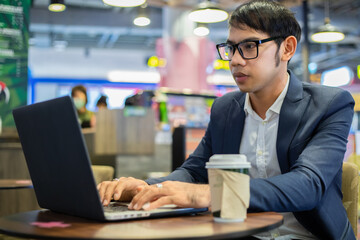 Asian businessmen are talking on the phone and drinking coffee while working