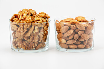 Pile of walnuts pistachios and almonds  in glass bowl on white background.