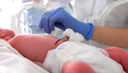 Nurse in blue gloves takes action to monitor and care for premature baby, selective focus. Newborn is placed in the incubator. Neonatal intensive care unit