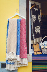 many traditional portuguese wool scarves and cotton cloth with different colors hanging from a window
