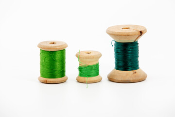 Reel or spool of green sewing thread isolated on white. Shallow depth of field. Close-up macro shot.