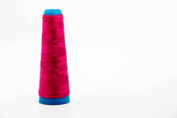 Reel or spool of red sewing thread isolated on white. Shallow depth of field. Close-up macro shot.